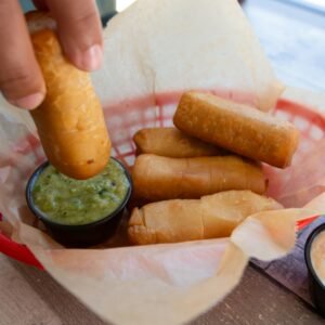 a person dipping a piece of food into a basket